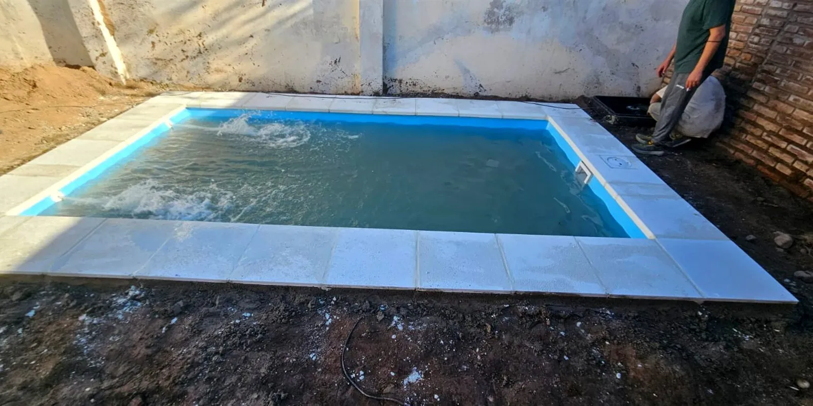 El mismo patio con la piscina instalada y llena